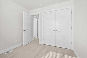 Unfurnished bedroom featuring light carpet and a closet