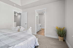 Bedroom with ensuite bathroom and light carpet