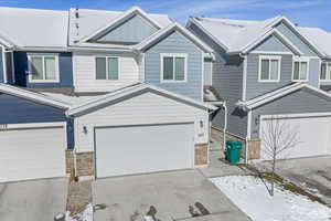 Craftsman-style house featuring stone siding, board and batten siding, driveway, and an attached garage