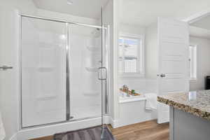 Full bath featuring vanity, a stall shower, light wood-style floors, and a garden tub