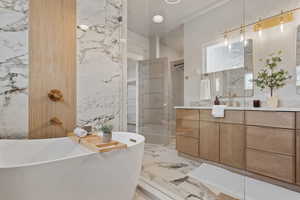 Primary full bath with vanity, beautifully tiled shower and a freestanding tub