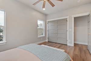 Primary bedroom with light wood-style floors, a closet, a ceiling fan, and recessed lighting