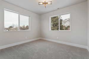 Bedroom with beautiful views - light carpet, plenty of natural light, and a chandelier