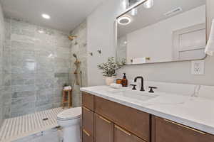 Ensuite bathroom with vanity, tiled shower, and recessed lighting