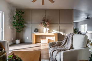 Living room featuring ceiling fan, wood finished floors, and a decorative wall
