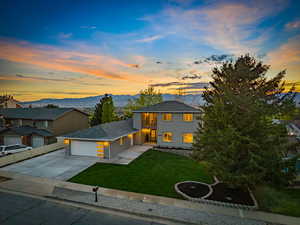 View of front of property with a front lawn, a garage, concrete driveway, and a balcony