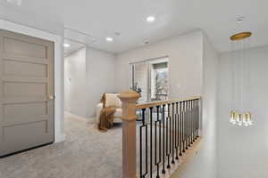 Corridor with an upstairs landing, light carpet, and recessed lighting