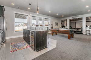 Kitchen featuring billiards table, light stone countertops, a kitchen bar, hanging light fixtures, and beverage cooler