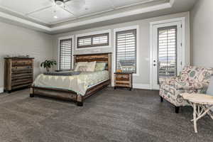 Bedroom featuring access to outside, a ceiling fan, dark colored carpet, and a tray ceiling