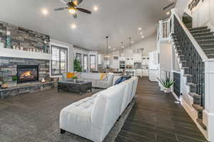 Living room with a fireplace, lofted ceiling, ceiling fan, wood tiled floors, and suspended lighting