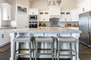 Kitchen with wood tiled floors, a kitchen bar, stainless steel appliances, and glass fronted cabinets