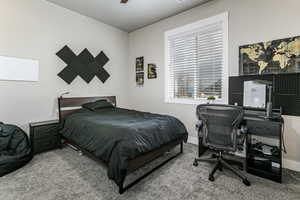 Carpeted bedroom with ceiling fan and a desk