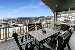 Wooden terrace featuring a residential view, grilling area, outdoor dining space, and a mountain view