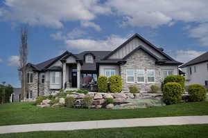 Craftsman house with stone siding, board and batten siding, a front lawn, and a shingled roof
