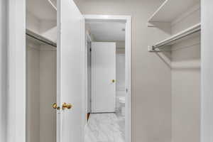 Walk in closet featuring light marble finish flooring