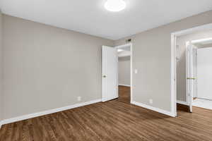 Unfurnished bedroom with dark wood-style flooring