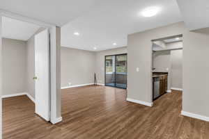 Kitchen featuring wood finished floors, dishwasher, dark stone countertops, and recessed lighting