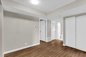 Unfurnished bedroom with dark wood-type flooring, a closet, and ensuite bath