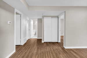 Unfurnished bedroom with a closet, connected bathroom, and wood finished floors