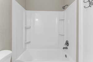 Full bathroom featuring washtub / shower combination and a textured wall