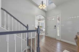 Entrance foyer featuring arched walkways, wood finished floors, a chandelier, and a high ceiling