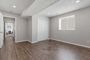 Unfurnished bedroom with dark wood-type flooring, a closet, a textured ceiling, and recessed lighting
