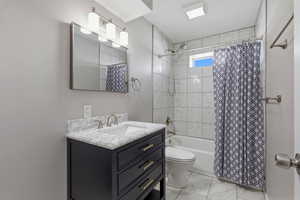 Full bath featuring vanity, shower / tub combo, and light marble finish flooring