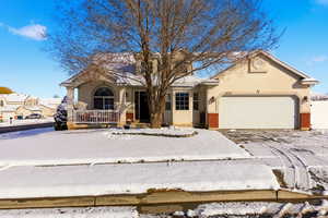 View of front facade featuring brick siding, an attached garage, a porch, and stucco siding