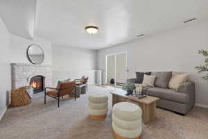 Living area with light carpet, a fireplace, and a textured ceiling