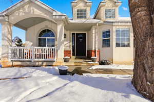 View of front of property featuring a porch, stucco siding, and brick siding