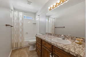 Bathroom featuring vanity, shower / bath combo with shower curtain, and light tile patterned floors