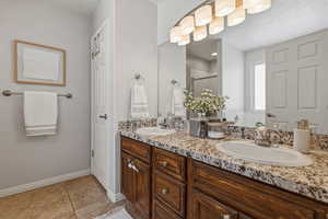 Bathroom featuring double vanity, a shower stall, and light tile patterned floors