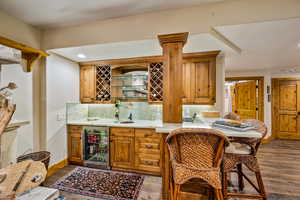 Indoor wet bar featuring beverage cooler, wood finish cabinets, recessed lighting, tasteful backsplash, and open shelves