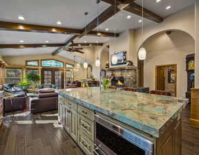 Kitchen with open floor plan, a fireplace, pendant lighting, dark wood-style flooring, and a kitchen island