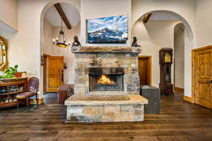 Living area with arched walkways, dark wood-type flooring, and a stone fireplace