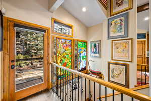 Corridor with wood finished floors and lofted ceiling with beams