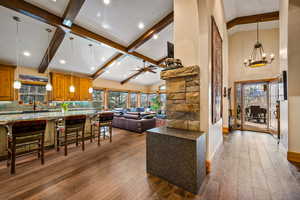 Living area with dark wood-style floors, vaulted ceiling, a ceiling fan, suspended lighting, and healthy amount of natural light