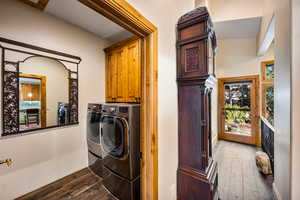 Laundry room with dark wood-type flooring, independent washer and dryer, plenty of natural light, and cabinet space