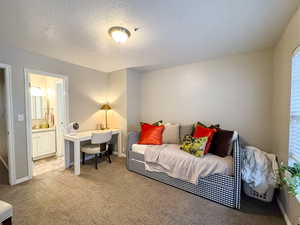 Bedroom featuring carpet floors, an office area, a textured ceiling, and connected bathroom