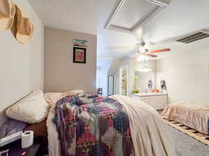 Bedroom featuring a textured ceiling, ensuite bathroom, carpet flooring, and a ceiling fan