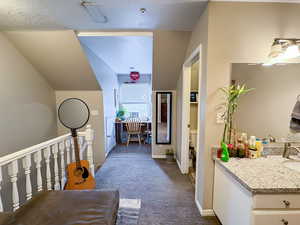 Corridor featuring dark colored carpet and a textured ceiling