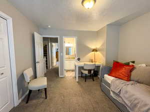 Living area featuring dark carpet, a textured ceiling, and a desk