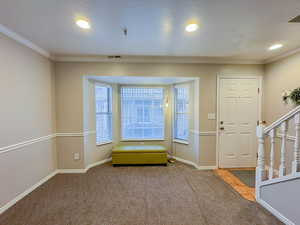 Carpeted foyer featuring crown molding, a textured ceiling, and recessed lighting