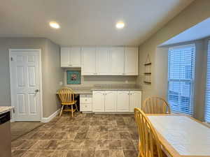 Kitchen with built in study area, white cabinets, dishwasher, and recessed lighting
