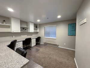 Office with built in study area, dark carpet, baseboard heating, and recessed lighting
