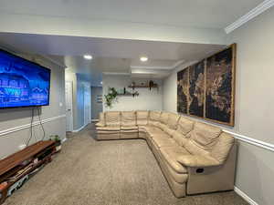 Carpeted living area with ornamental molding and recessed lighting