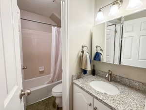 Bathroom with vanity, a textured ceiling, and shower / tub combo