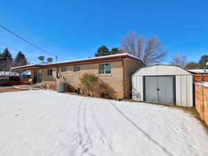 Rear view of property with a storage shed and brick siding