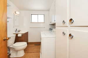 Half bath with vanity, light wood-style flooring, and washing machine and clothes dryer