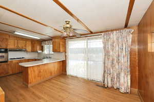 Kitchen featuring wood finish cabinets, light countertops, a peninsula, a ceiling fan, and stainless steel oven